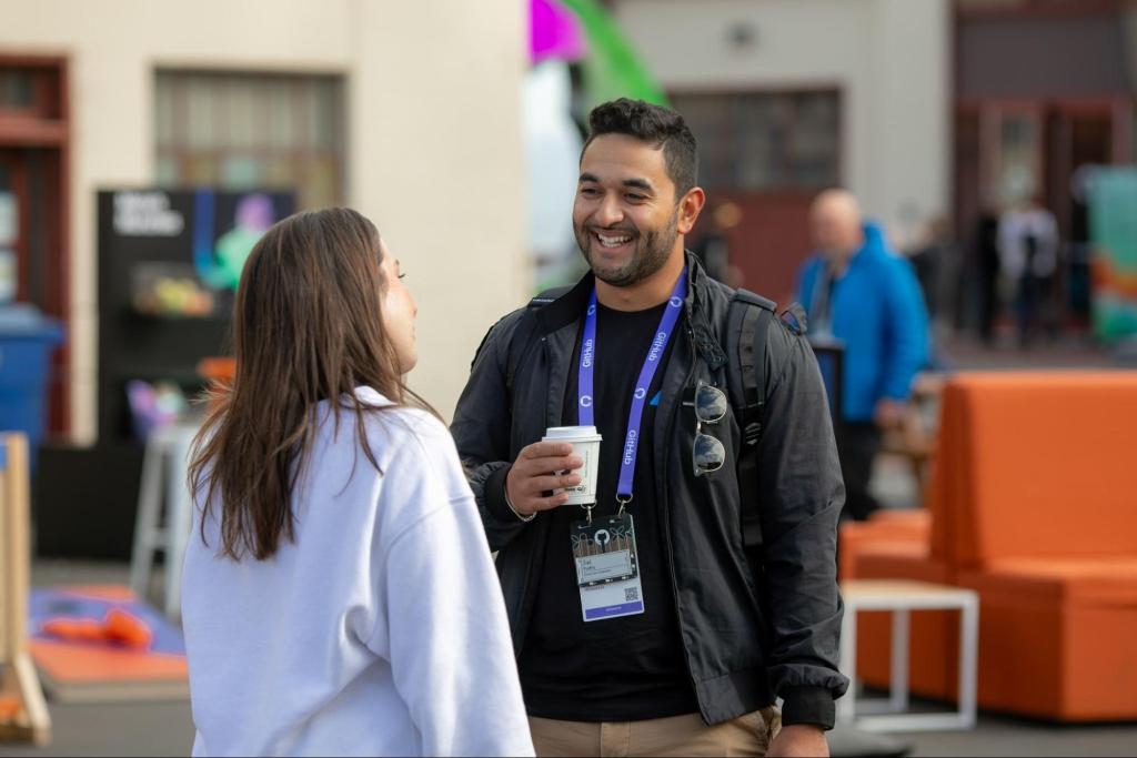 Two people talking and drinking coffee at GitHub Universe.