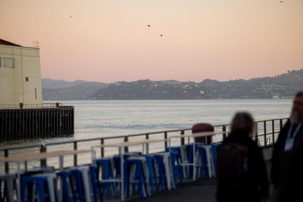 Sunset view across the bay with birds flying over water and hills in background.